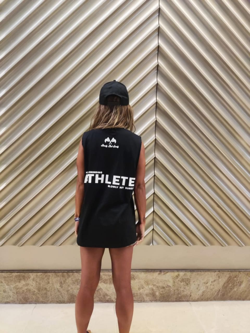 Jasmin from behind, facing a wall in an Athlete shirt